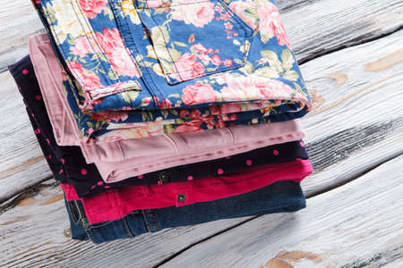 Pink trousers and casual jeans. Stack of colorful folded pants. Quality materials and interesting...