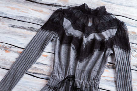 Gray dress with black inserts. Dark dress on wooden background. Showcase with top quality item....