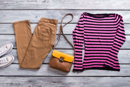 Pink and black striped top. Brown trousers and striped pullover. Fashionable clothing in showroom. Best items from brand shop.の写真素材
