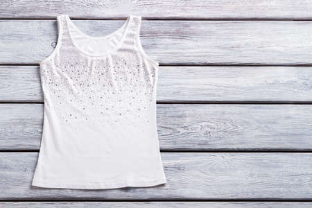 Rhinestone tank top. Lady's white casual top. Summer garment on wooden shelf. Item sold at fashion...