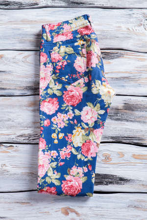 Blue pants with floral print on wooden background.の写真素材