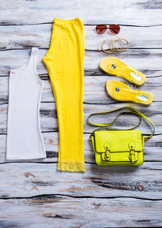White top and flip flops. Yellow pants with lime handbag.の写真素材