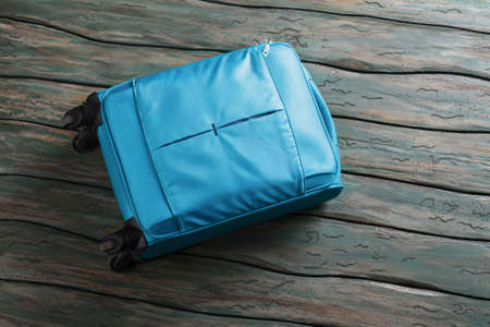 Blue luggage bag on wheels. Suitcase on green wooden background. It's time to leave. Don't forget your baggage.の写真素材