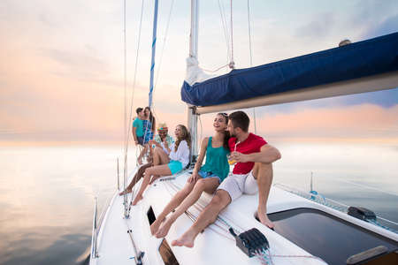 Young people sitting on yacht.