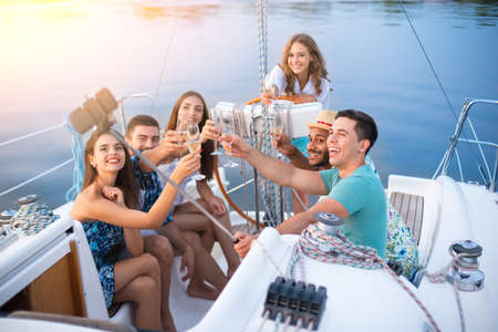 People with drinks taking selfies on yacht.の写真素材
