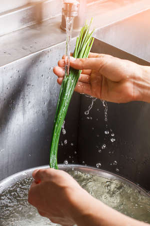 Man's hands wash green onion.の写真素材