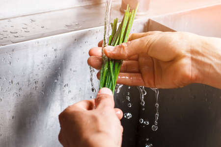 Man's hands washing green onion.の写真素材