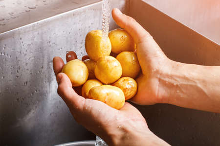 Man's hands washing potatoes.の写真素材