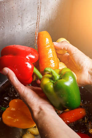 Hands washing carrot and paprika.の写真素材