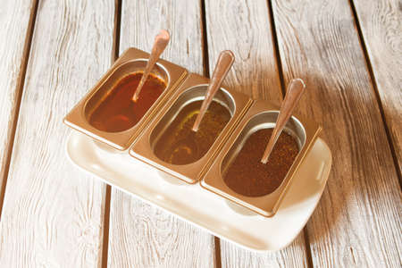 Silver containers with sauce. Sauce containers on wooden background. Liquid mixed with herbs. Seasonings for your meal.の写真素材