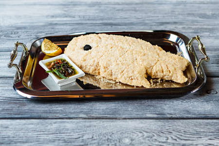Breaded fish on tray. Fish with lemon and herbs. Dorado fish in sea salt. Healthy meal of seafood.