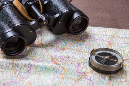 Binoculars and compass on map. Compass lying on a map. Choose the best route. These things belong to...