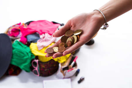 Girl's hand with coins. Open suitcase in the background. Chance to take a journey. New life far from home.の写真素材