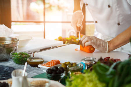 Hand with knife cuts carrot. Man cooking food at table. Add some bits of carrot. This dish lacks vitamins.の写真素材