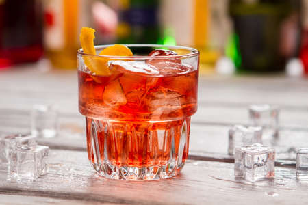 Dark orange drink in glass. Ice cubes and lemon peel. Negroni served at local bar. Vermouth and gin.の写真素材