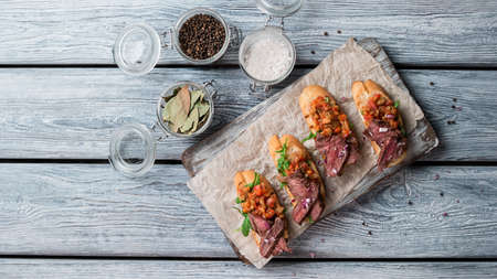 Small sandwiches with meat. Jars with salt and pepper. Tasty and crispy bruschetta. Freshly cooked...
