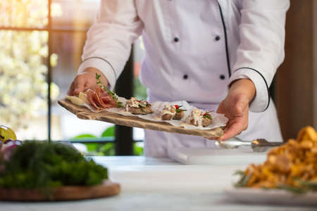 Hands hold board with meat. Bacon and green herb. Beef medallions with roquefort sauce. Enjoy your dinner.の写真素材