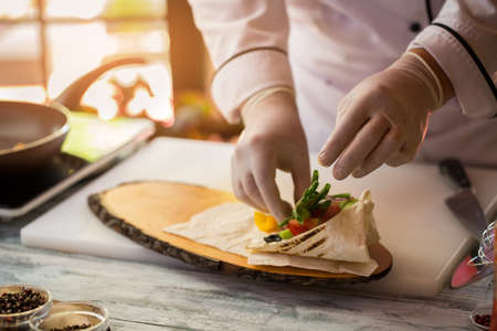 Hands touching cut vegetables. Pita bread and green onion. Experienced chef cooks food. Breakfast for a gourmet.の写真素材