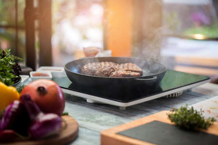 Meat on a frying pan. Brown colored steak. New electric cooker. Prepare lunch for gourmet.の写真素材