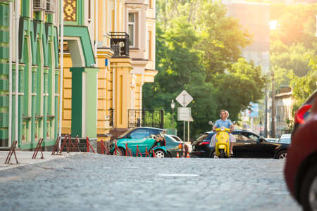 People riding on a scooter. Street during daytime. Travelling through historic places. Morning on...