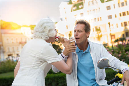 Mature couple eating ice cream. People on city background. Go on vacation in summer. Best time spent...