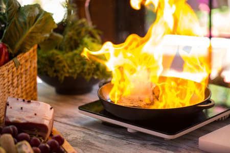 Flame in a pan. Meat and yellow fire. Special methodology of cooking. It's hot in the kitchen.の写真素材