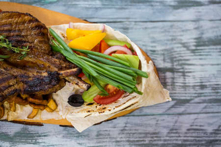 Cooked meat with mushrooms. Pita with pieces of vegetables. Grilled pork and green onion. Tasty lunch in local cafe.の写真素材