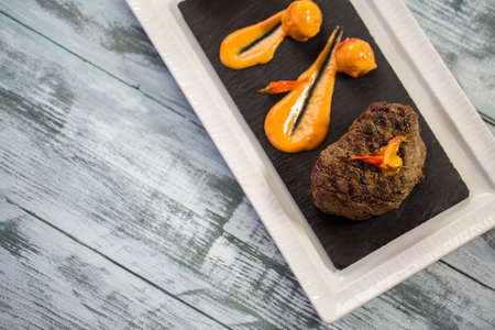 Cooked meat and sauce. Plate on gray wooden background. Appetizing pepper steak. Welcome to the restaurant.の写真素材