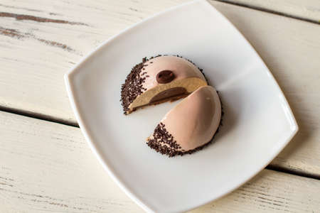 Small cake with brown filling. Two halves of glazed dessert. Fresh coffee mousse cake. Snack from pastry shop.の写真素材