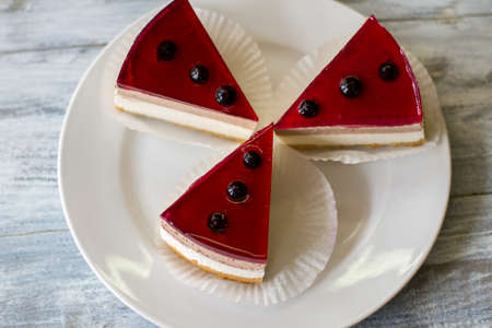 Pieces of cake on plate. Dessert decorated with currant. Cheesecake with jelly. Natural components and proven recipe.の写真素材
