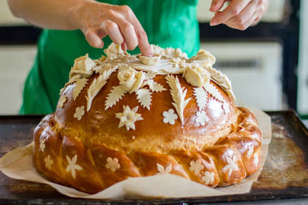 Lady's hand touching decorated pastry. Loaf of bread on tray. Beautiful wedding bread. Stay true to traditions.の写真素材