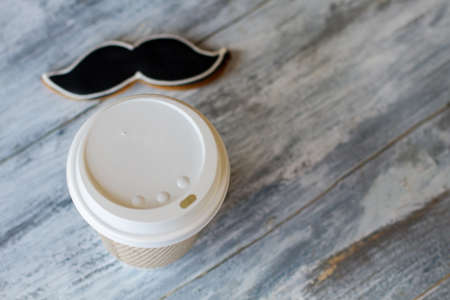 Hot drink cup and biscuit. Moustache cookie of black color. Dessert for true men. Tea and pastry in cafe.の写真素材