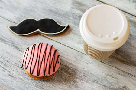 Cookies and hot drink cup. Glazed biscuit shaped as moustache. Fresh coffee and pastry. Morning dessert of a gentleman.の写真素材
