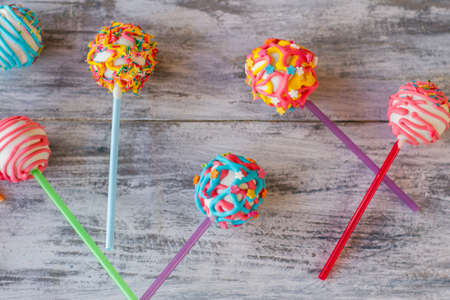 Sweets on sticks. Candies on gray wooden background. Delicious cake pops. How to surprise the kids.