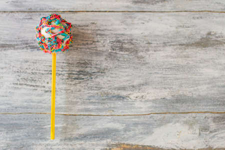 Cake pop with sprinkles. Candy on gray background. Eat well and have fun. Boost your mood.