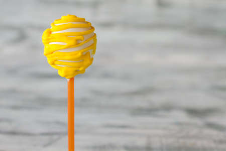 Cake lollipop with frosting. Dessert on gray background. Birthday snack for a kid. Easiest way to lift mood.の写真素材