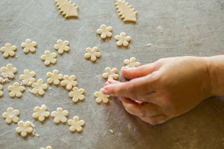 Hand touches flower from dough. Little pieces of raw pastry. Baker makes decoration for food. Recipe and artwork.の写真素材