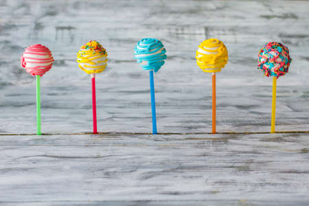 Five cake pops. Candies with glaze and sprinkles. New design of sweets. Bright color and good taste.