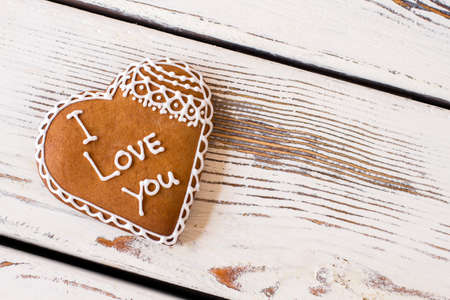 Heart shaped cookie with inscription. Biscuit of brown color. Convey message through a gift. Confession in love.の写真素材