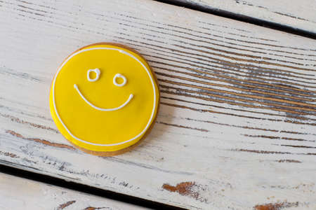 Smiley biscuit on wooden background. Round cookie with glaze. Simplest recipe of great mood. Dessert charges you with energy.の写真素材