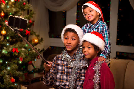 Three boys take Christmas selfie. Kids take selfie on Christmas. Moment worth capturing. Good mood for Christmas photo.の写真素材