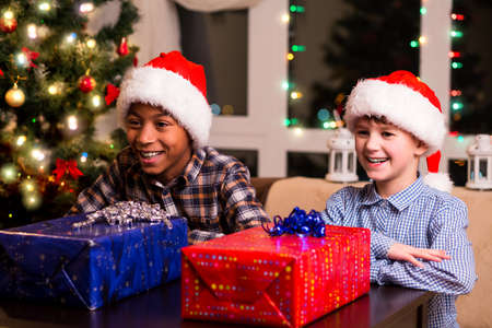 Two boys with Christmas presents. Boys waiting to open presents. It's so hard to wait. Few seconds before joy.の写真素材