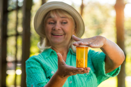Woman with pill bottle smiling. Lady holding medicine. New vitamin formula. Drug that strengthens...