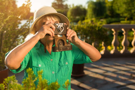 Mature woman holding camera. Lady in summer hat. What a wonderful view. Few photos of nature.の写真素材
