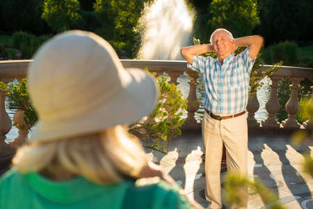 Senior man with raised arms. Elderly male is smiling. Take a photo near fountain. Best place I've been to.の写真素材