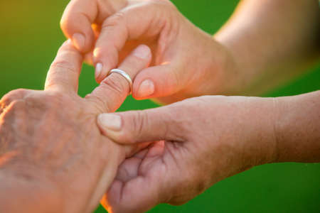 Woman puts ring on man. Hands of old couple. I won't ever leave you. Love is mutual.