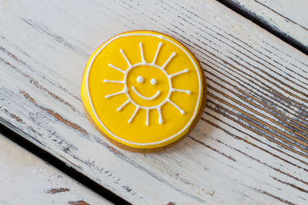 Yellow sun biscuit. Top view of iced cookie. Tasty homemade pastry with glaze. World will smile to you.の写真素材