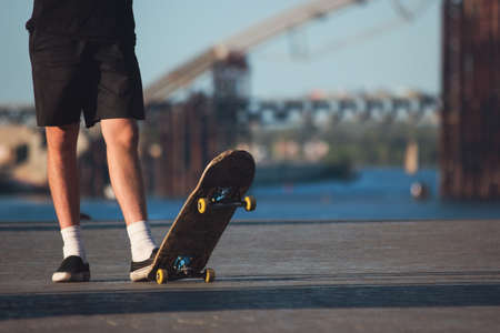 Guy with skateboard outdoor. Legs of skateboarder standing. Sport of young and fearless. For those who love risk.の写真素材
