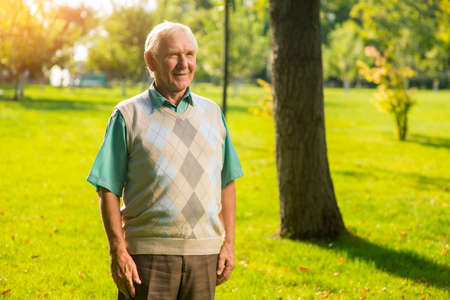 Senior man standing outdoor. Person with gray hair smiling. Realizing the passage of time. I achieved everything I wanted.の写真素材