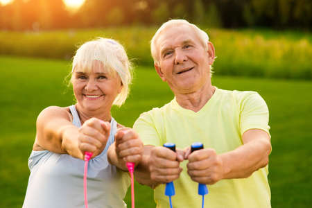 Smiling couple of seniors outdoor. People holding skipping ropes. Small victories in sport. Improve...
